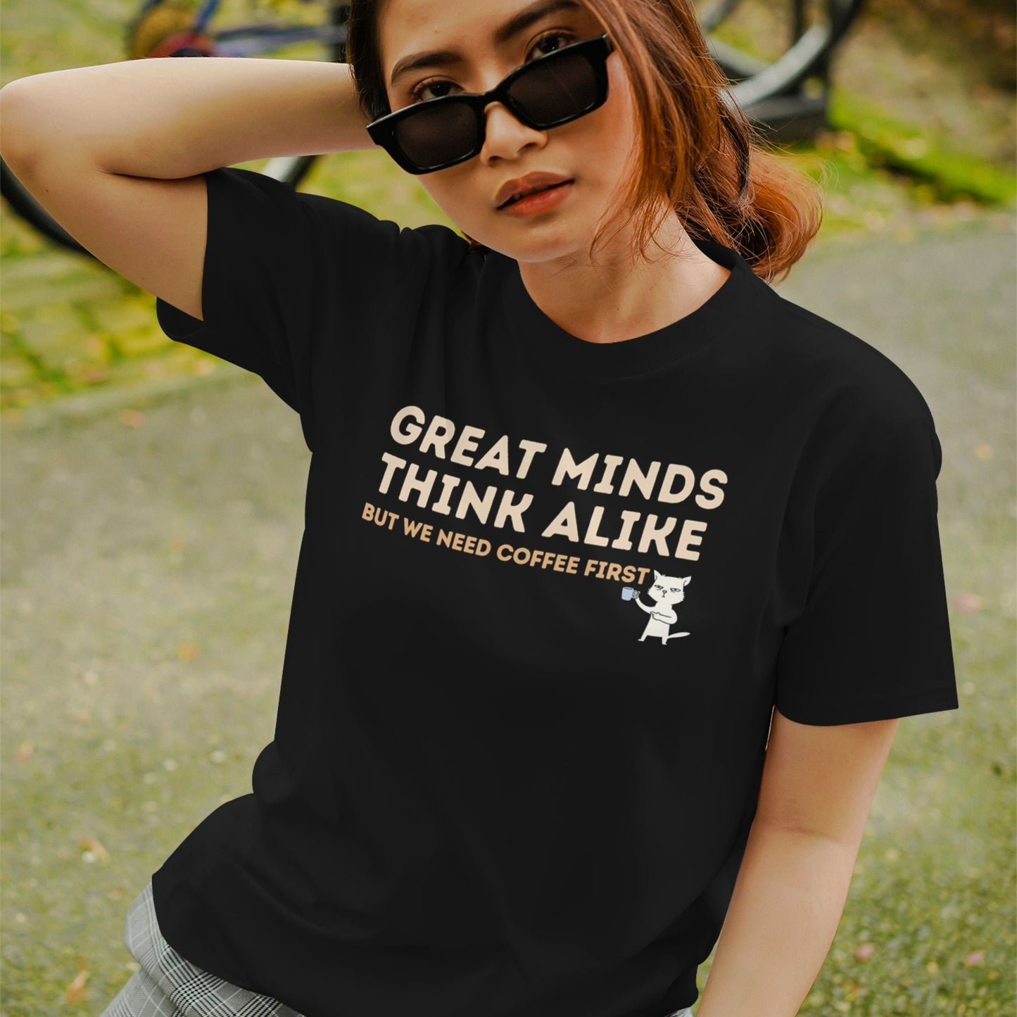 Black cotton T-shirt featuring the quote "Great Minds Think Alike, But We Need Coffee First" with a cute cat holding a coffee mug.