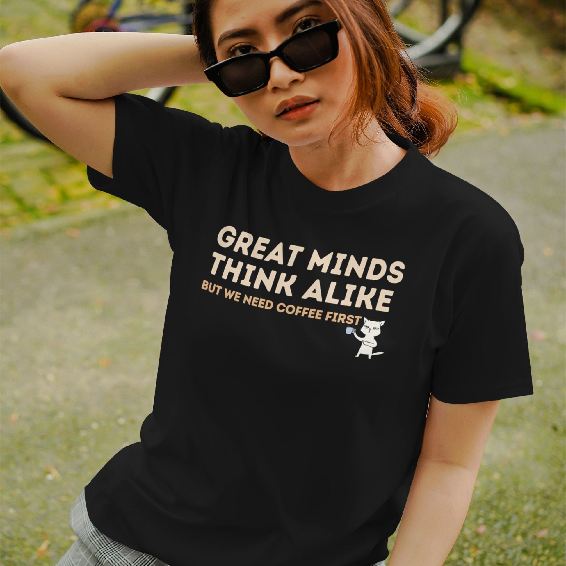 Black cotton T-shirt featuring the quote "Great Minds Think Alike, But We Need Coffee First" with a cute cat holding a coffee mug.