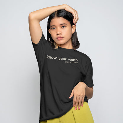 Unisex minimalist quote t-shirt showing the text “know your worth then add taxes,” simple black graphic tee for everyday wear.